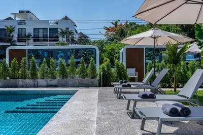 a pool with lounge chairs and an umbrella at Apple House with pool&breakfast Steps from the Sea in Ban Lum Fuang