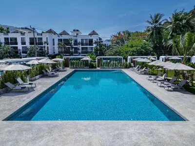 a swimming pool with chairs and umbrellas at a resort at Apple House with pool&breakfast Steps from the Sea in Ban Lum Fuang