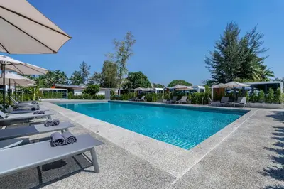 a swimming pool with chairs and umbrellas at a resort at Apple House Bangtao with terrace Pool & Beach in Ban Lum Fuang