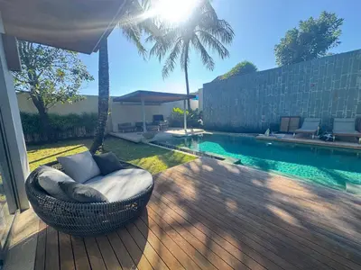 a wicker chair sitting on a deck next to a swimming pool at Anchan Grand Residence Bangtao in Ban Pak Lak