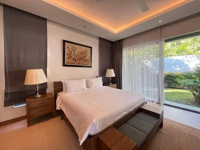 a bedroom with a bed and a large window at Anchan Grand Residence Bangtao in Ban Pak Lak