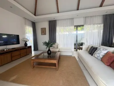 a living room with a white couch and a tv at Anchan Grand Residence Bangtao in Ban Pak Lak