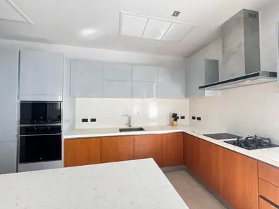 a kitchen with wooden cabinets and a black appliance at Anchan Grand Residence Bangtao in Ban Pak Lak