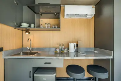 a small kitchen with a sink and two stools at Seaside Apple House, Pool & Morning Breakfast in Ban Lum Fuang