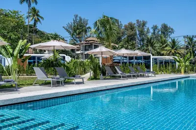 a pool with chairs and umbrellas next to a resort at Apple House Comfort coziness beach pool, breakfast in Ban Lum Fuang