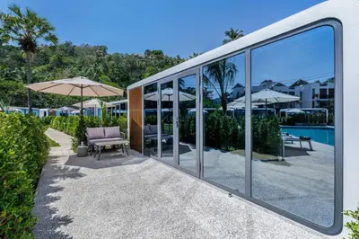 a building with glass windows and a pool at Apple House Bangtao 1 Min Beach Pool & Breakfast in Ban Lum Fuang