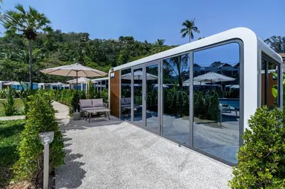 a glass building with a chair and an umbrella at Private Pool Apple House, Sea & Breakfast Bangtao in Ban Lum Fuang