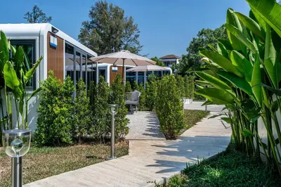a walkway with an umbrella next to a building at Private Pool Apple House, Sea & Breakfast Bangtao in Ban Lum Fuang