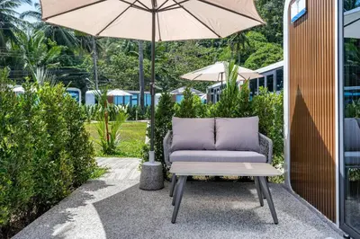 a chair sitting under an umbrella on a patio at Apple House Beach Access, Pool & Breakfast in Ban Lum Fuang