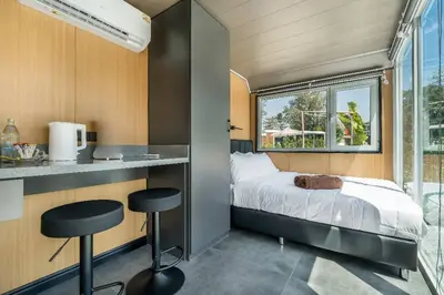 a small bedroom with a bed and two stools at Apple House Stylish Seaside Retreat with Breakfast in Ban Lum Fuang