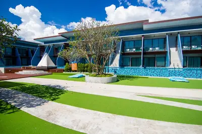 a building with a green lawn in front of it at The Phu Beach Hotel - SHA Plus in Ao Nang Beach