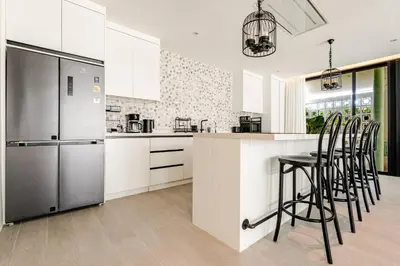a kitchen with white cabinets and bar stools at Sarah Place Private Tropical Villa in Ban Pak Lak