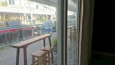 a bench and two stools in front of a window at Gentle Guesthouse in Patong Beach