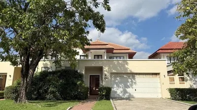 a white house with a tree and a garage at Tropical Thai style 4 bedroom pool villa in Laguna Phuket