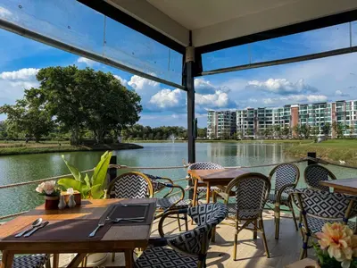 a patio with tables and chairs and a view of a river at Cozy 1 Bdr Royal Lee Nayang beach in Ban Bo Han