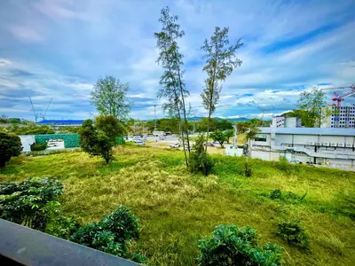 a field of grass with trees and a building at Family Space Condo 2 Bdr BangTao in Ban Thalat Choeng Thale