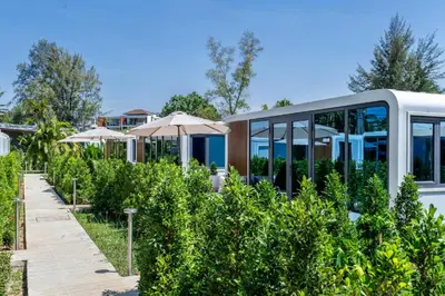 a garden with umbrellas in front of a building at Apple House Bangtao Pool, Terrace & Breakfast in Ban Lum Fuang