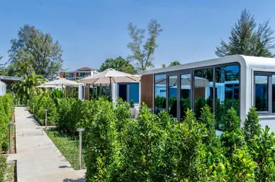 a house in a garden with umbrellas at Apple House Bangtao Pool, Terrace & Breakfast in Ban Lum Fuang