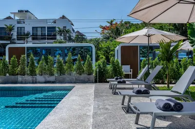 a pool with lounge chairs and an umbrella at Beachside Apple House Pool & Terrace in Bangtao in Ban Lum Fuang