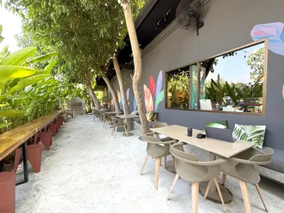 a restaurant with tables and chairs and trees at Apple House Seaside Escape with Pool & Breakfast in Ban Lum Fuang