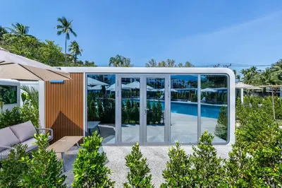 a house with a pool and glass walls at Apple House Seaside Escape with Pool & Breakfast in Ban Lum Fuang