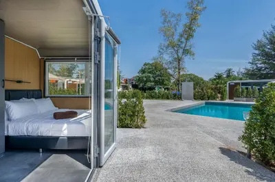 a bed in a glass room next to a swimming pool at Apple House Phuket Pool, Terrace, Breakfast, Beach in Ban Lum Fuang