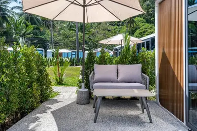 a chair and an umbrella on a patio at Apple House Phuket Pool, Terrace, Breakfast, Beach in Ban Lum Fuang