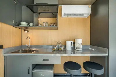 a small kitchen with a sink and two stools at Apple House by the Sea, Bangtao Area in Ban Lum Fuang