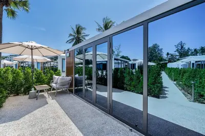 a glass house with a chair and an umbrella at Apple House by the Sea, Bangtao Area in Ban Lum Fuang