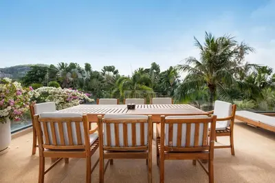 a table and chairs on a balcony with palm trees at Peaceful Penthouse @ Lotus Gardens Layan Beach in Layan Beach