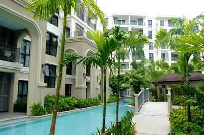 a swimming pool in front of a building with palm trees at The Title Legendary by TVC company in Bang Tao Beach