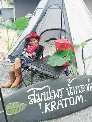 a little girl sitting in a chair in front of a tent at Kalaland Patong camp in Patong Beach
