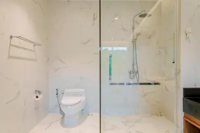a bathroom with a toilet and a glass shower at Niva Villa - Modern & Lake View near Phuket town in Ban Bang Khu