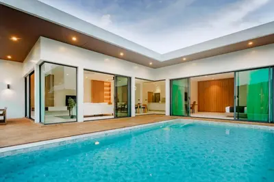 an indoor swimming pool in a house with glass walls at Niva Villa - Modern & Lake View near Phuket town in Ban Bang Khu