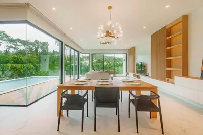 a dining room with a table and chairs and a pool at Niva Villa - Modern & Lake View near Phuket town in Ban Bang Khu