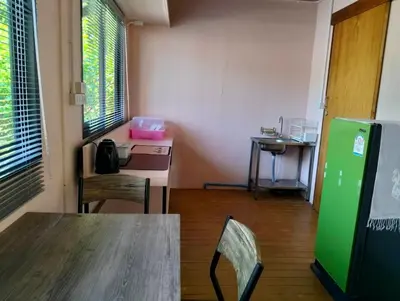 a room with a table and a green refrigerator at Parin House Homestay - Koh Yao Noi in Ko Yao Noi