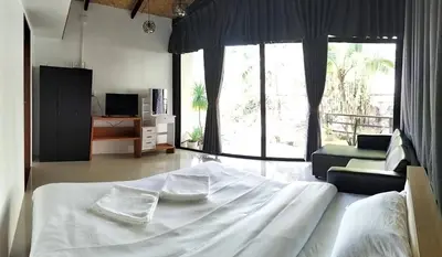 a bedroom with a large white bed and a living room at Parin House Homestay - Koh Yao Noi in Ko Yao Noi
