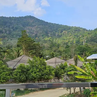 a group of houses with a mountain in the background at Kamala House in Kamala Beach
