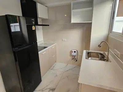 a small kitchen with a black refrigerator and a sink at Kamala House in Kamala Beach