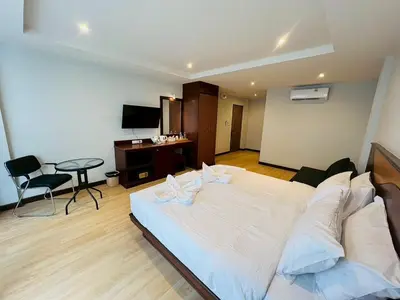 a bedroom with a large white bed and a desk at One Houses in Patong Beach
