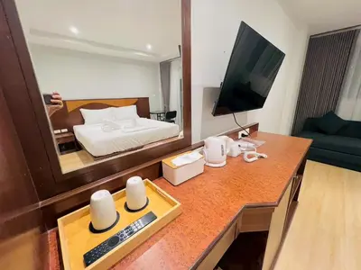 a room with a bed and a desk with a television at One Houses in Patong Beach