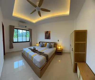 a bedroom with a large bed with a ceiling fan at Lai Thai Villa 5 in Rawai Beach