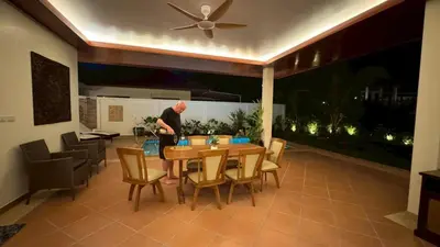 a man standing in a living room with a table and chairs at Lai Thai Villa 5 in Rawai Beach
