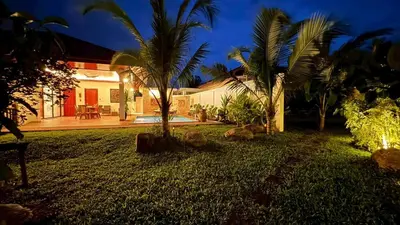 a house with a yard with palm trees in front of it at Lai Thai Villa 5 in Rawai Beach