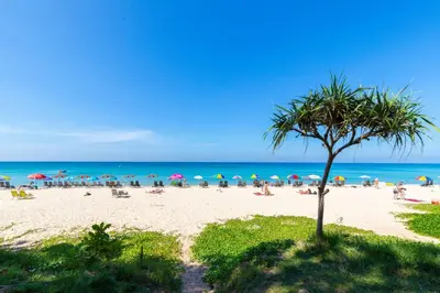 a beach with umbrellas and people on the sand at Laguna Cozy 3 bedroom town house 800m to beach in Laguna Phuket