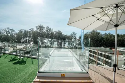 a glass enclosure on a building with an umbrella at New Boutique Studio, Near the Sea in Layan Beach