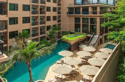 an outdoor swimming pool with umbrellas and a hotel at The Proud Karon Phuket - New 1BR Apartment 6floor in Karon Beach