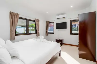 a bedroom with a white bed and a tv at V278 Quiet Poolside 3BR Villa for Relaxed Stays in Ban Bang Chak