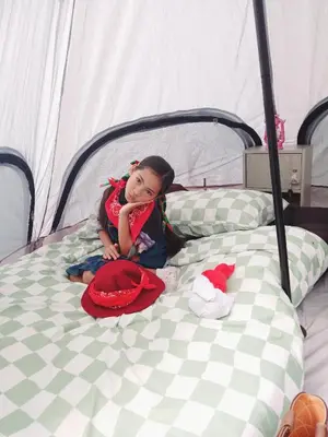 a little girl is sitting on a bed at Kalaland camp tant Patong in Patong Beach