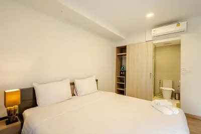 a bedroom with a large white bed and a bathroom at Apartments in the center of Laguna in Laguna Phuket